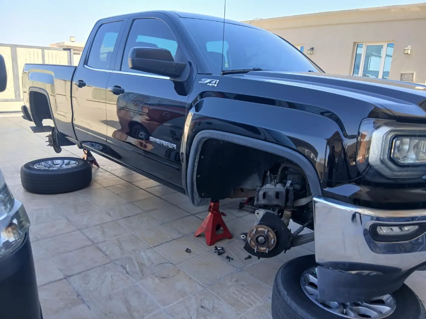 GMC Sierra on jack stands for mobile tire and brake work in Qatar